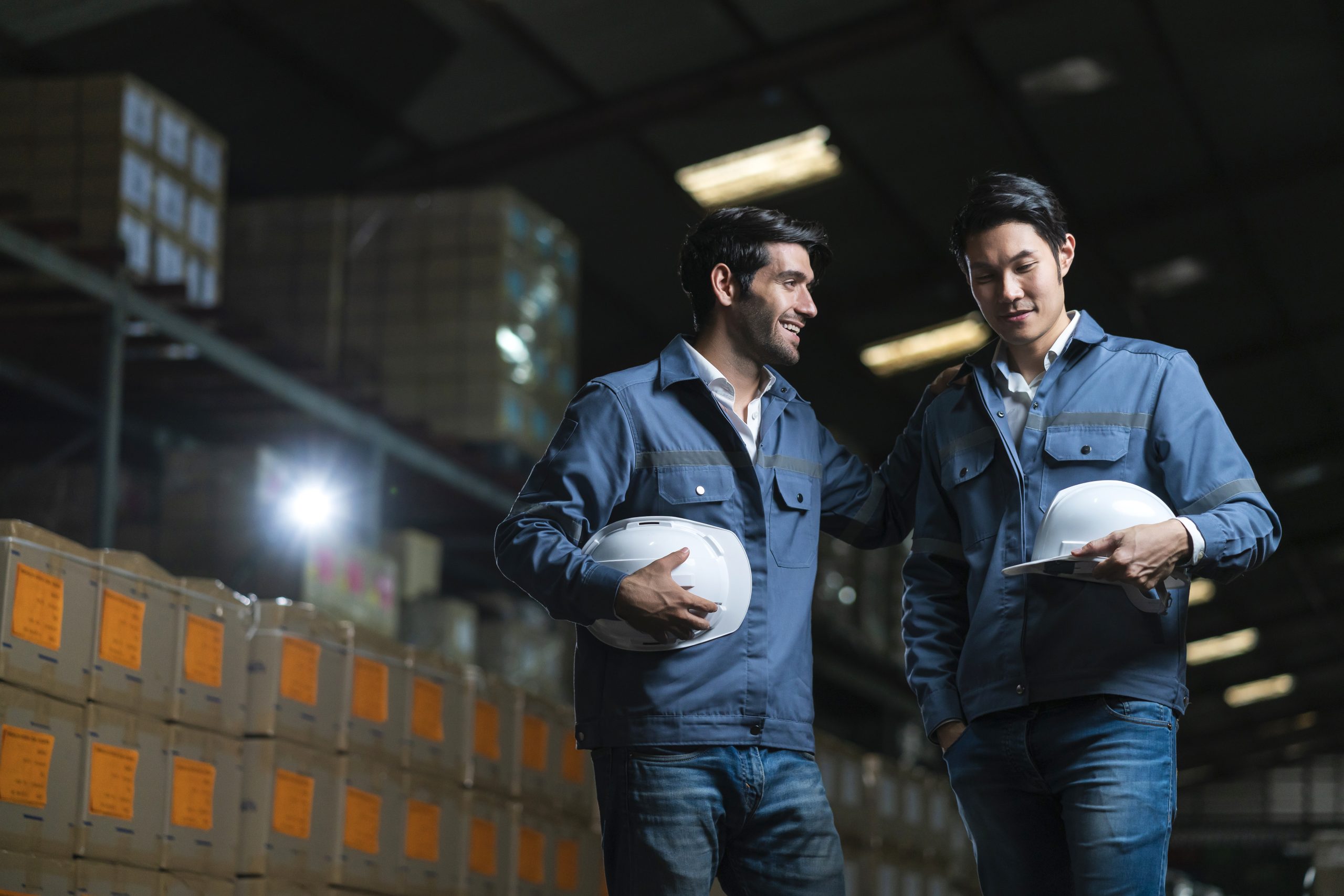 relax casual male asian and caucasian engineer staff worker in uniform happy conversation after work in warehouse distribution background